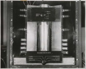 Interior control panel of the UNIVAC Memory Demonstration Unit showing the mercury delay line tank in center flanked by rows of vacuum tubes mounted in plug-in chassis on each side. Operation Selector Switch and Oscilloscope Selector Switch visible. EMCC, circa 1951.