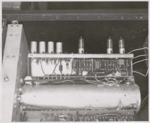 Close-up of a UNIVAC recirculation amplifier chassis with front panel removed, showing miniature vacuum tubes and associated circuitry mounted above the mercury delay line tank. EMCC, circa 1951.